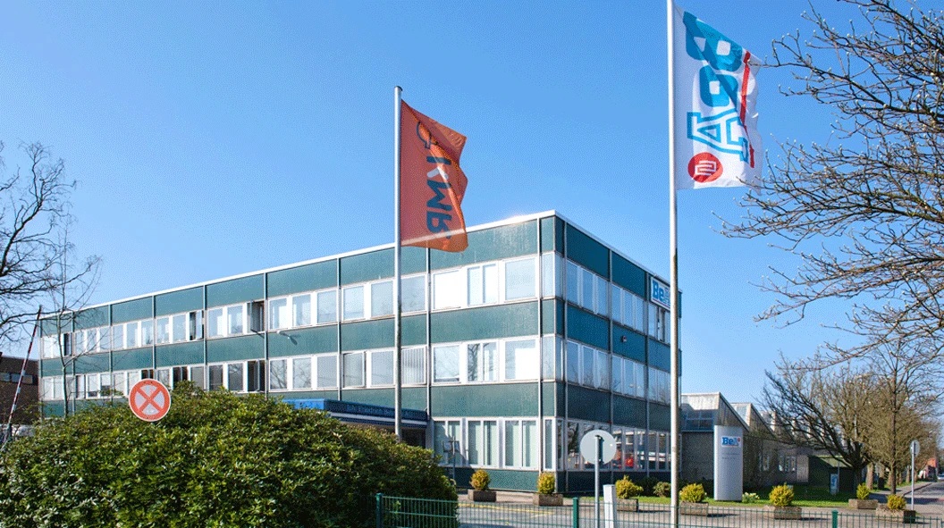 WORKPRO industrial building in Germany with a glass-fronted facade, branded flags and landscaped grounds WORKPRO industrial building in Germany with a glass-fronted facade, branded flags and landscaped grounds