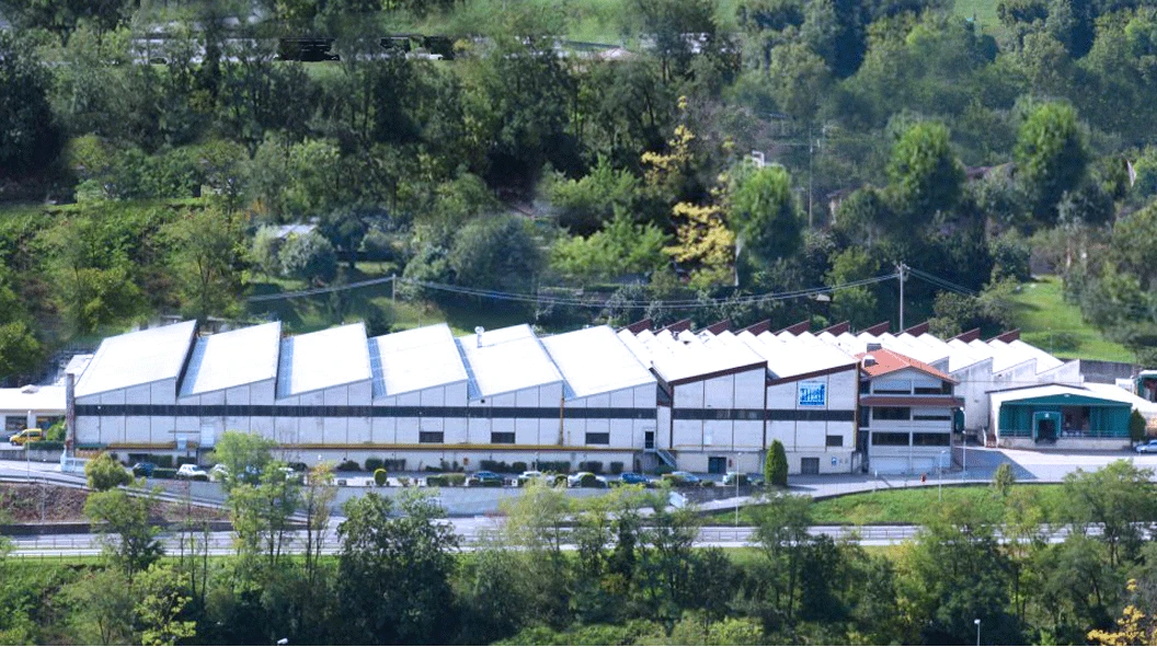 WORKPRO industrial facility in Italy with a repeating sawtooth roof, roadside frontage and a wooded hillside WORKPRO industrial facility in Italy with a repeating sawtooth roof, roadside frontage and a wooded hillside